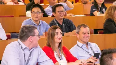In a lecture room, a diverse group of participants is fully engaged in a presentation.
